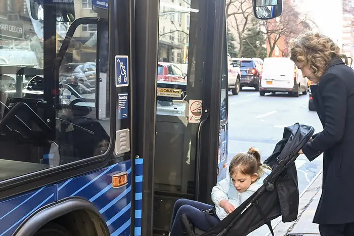 A New York City mother brings her child in a stroller onto an MTA bus.